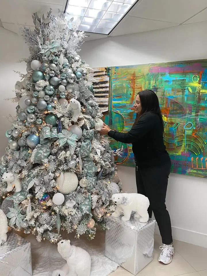 A designer installing a teal and silver Christmas tree