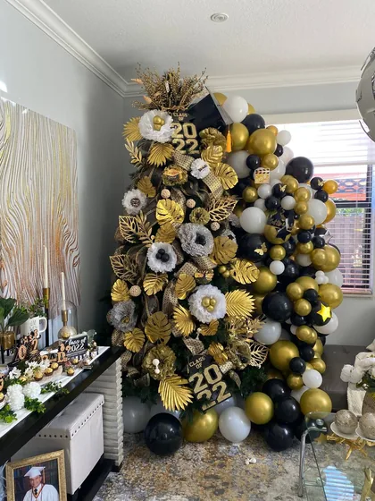 Black and gold graduation tree with a balloon garland, Class of 2022, in a Miami home