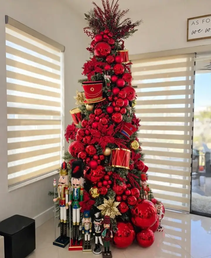 Nutcracker figures standing at the base of a large red Christmas tree